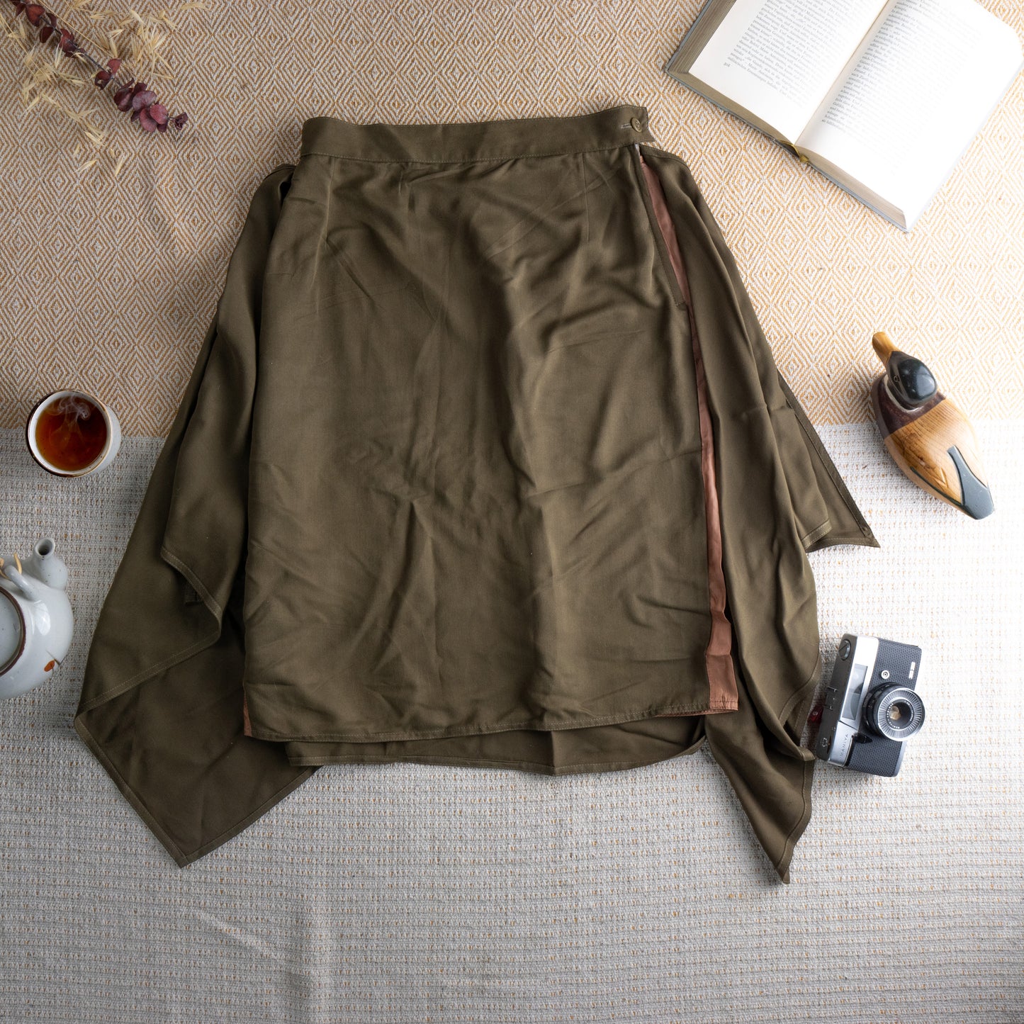 Vintage Max Mara 90s Silk Cupro Midi Skirt – olive army green fluid silk-cupro, high waist with single button closure, dramatic deep side slits revealing blush lining, asymmetric draped hem, minimalist Italian luxury, flat lay editorial shot