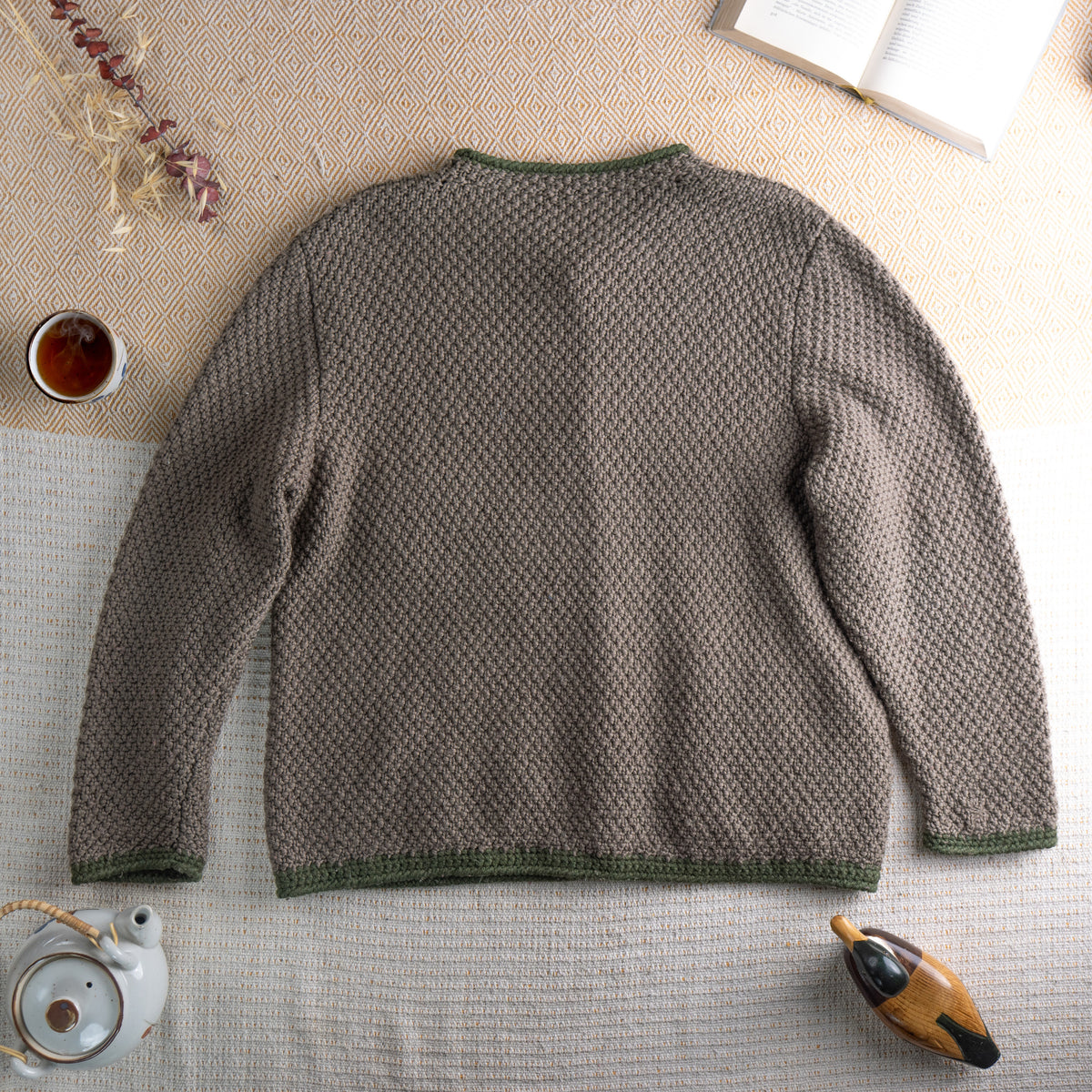 back view Vintage Italian Alpine Udine Hand Knit Oversized Cardigan – taupe brown chunky knit with green trim, intarsia pastoral scene featuring blue sky, yellow sun, green trees and white goose, silver coin buttons, two patch pockets, round neckline, long sleeves, artisan folk craft, flat lay editorial shot
