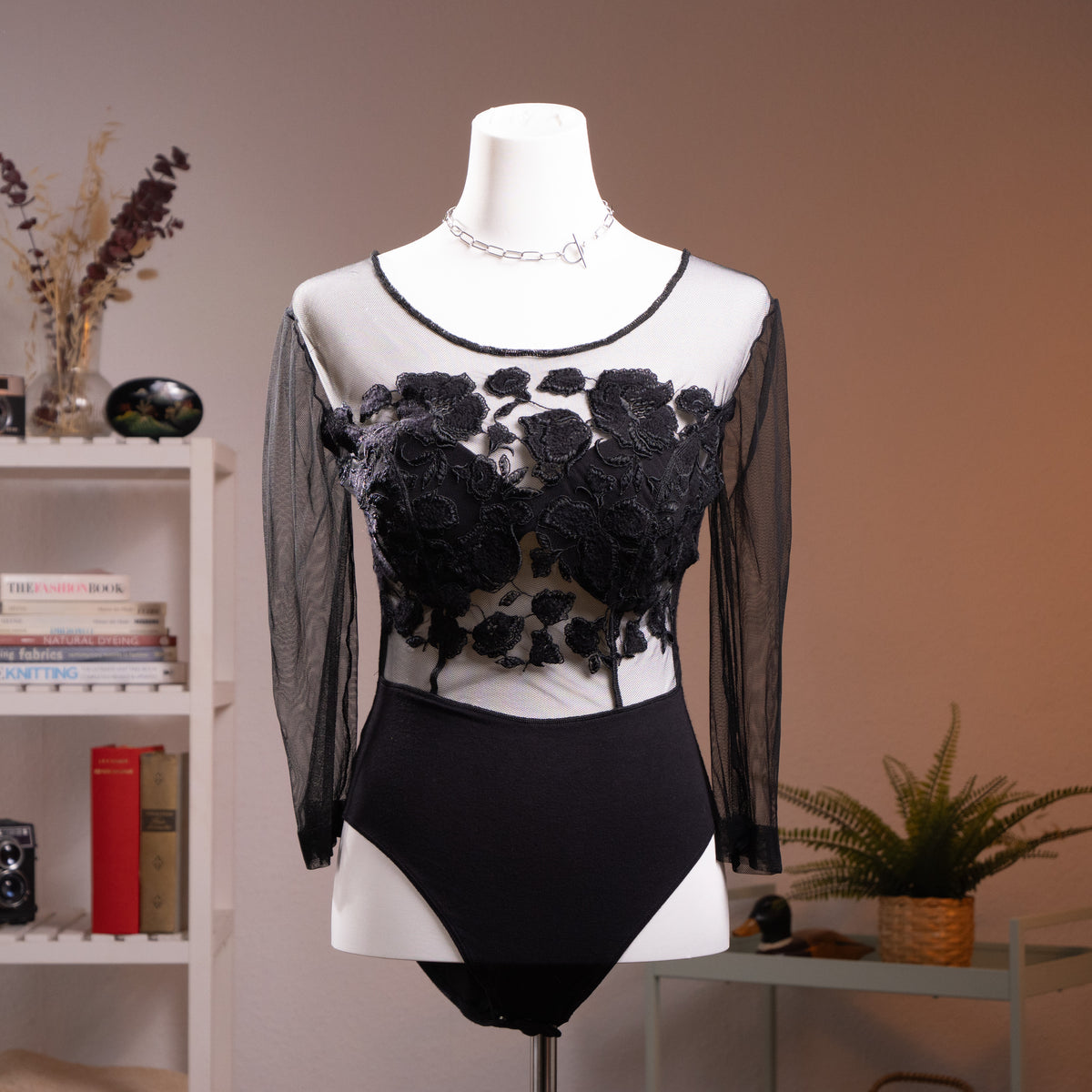 Archival La Perla Tricot 90s Long Sleeve Mesh Bodysuit – sheer black mesh with dramatic 3D chenille rose appliqué across chest and torso creating tattoo effect, round neckline with satin trim, long sleeves, black opaque high-cut brief base, Italian museum grade lingerie, product shot on dress form