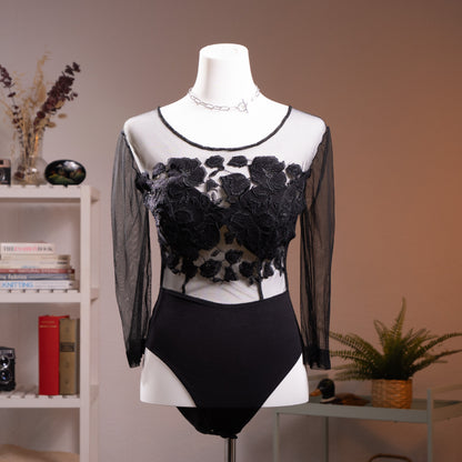 Archival La Perla Tricot 90s Long Sleeve Mesh Bodysuit – sheer black mesh with dramatic 3D chenille rose appliqué across chest and torso creating tattoo effect, round neckline with satin trim, long sleeves, black opaque high-cut brief base, Italian museum grade lingerie, product shot on dress form