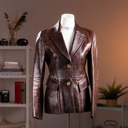 Archival Kenzo Jungle 90s Buttery Brown Nappa Leather Blazer – rich chocolate brown soft nappa leather with notched lapels, two-button single-breasted front with decorative wood-effect buttons, structured waist seaming with ribbed panel detail, flap pockets, long sleeves, floral botanical lining, product shot on dress form
