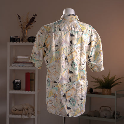 Archival Courrèges Paris 90s Modernist Abstract Print 100% Linen Shirt – cream linen with all-over geometric abstract print in teal, yellow, black and lavender, point collar, short sleeves, button-front, oversized unisex fit shown knotted at waist, avant-garde museum grade piece, product shot on dress form