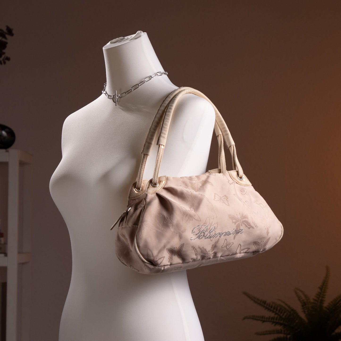 Blumarine Y2K Baguette Bag by Anna Molinari – blush beige nylon with tone-on-tone butterfly jacquard print, rhinestone crystal "Blumarine" script logo, dual rolled leather top handles with gold ring hardware, zip closure, Made in Italy, shown on dress form
