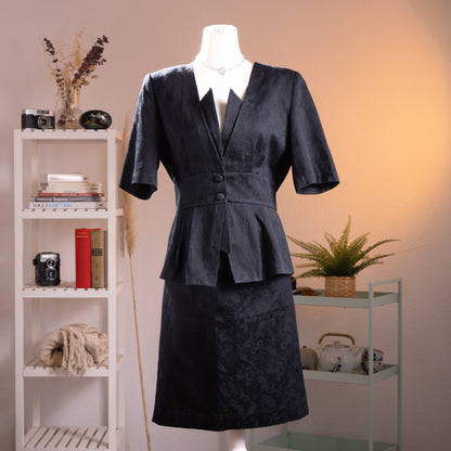 Archival Loris Azzaro Paris 80s NOS Power Suit – black cotton jacquard two-piece skirt set, structured blazer with deep V-neckline, zigzag lapel detail, two-button waist closure, short sleeves, peplum hem, matching A-line midi skirt, museum quality, product shot on dress form
