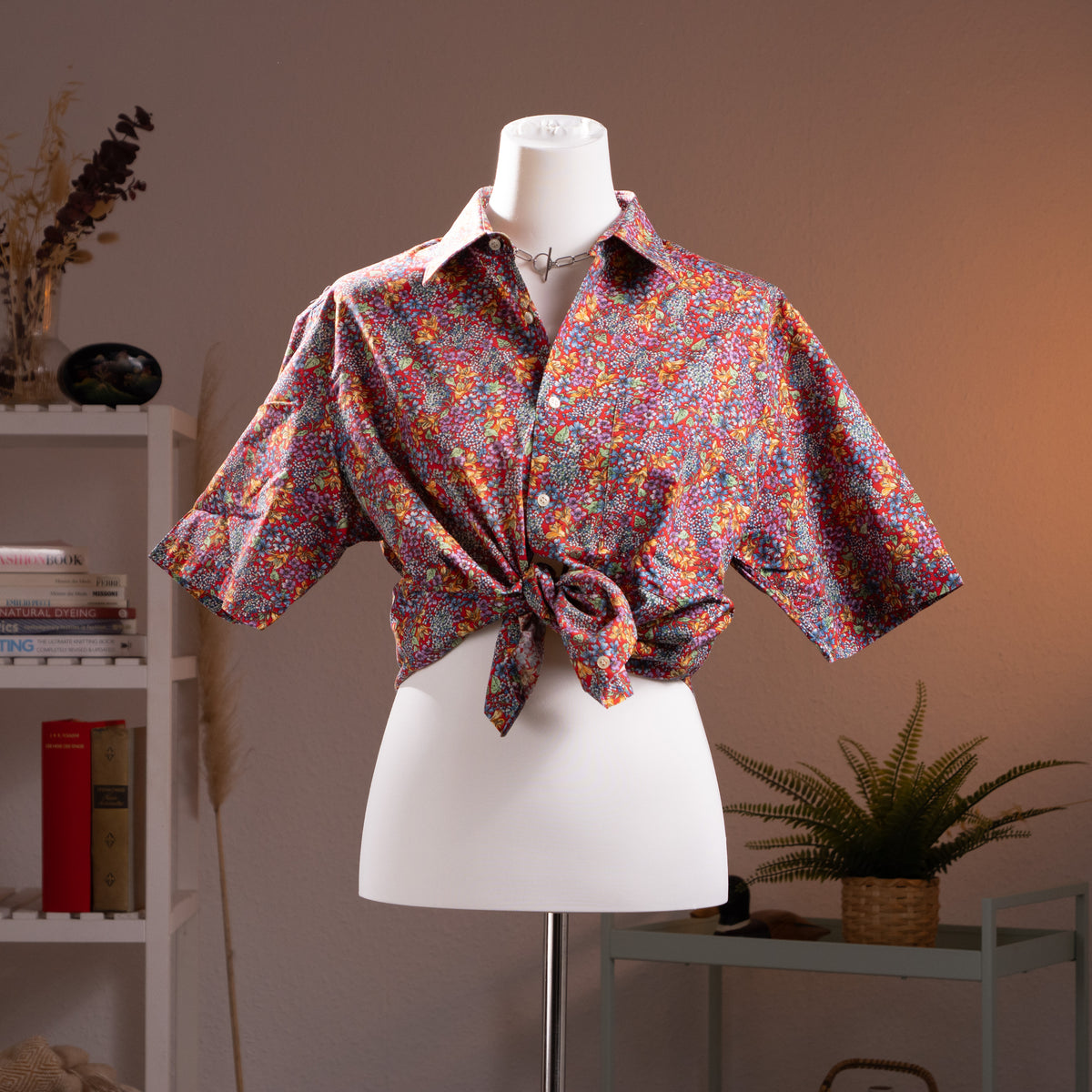 Archival Nina Ricci NOS Deadstock 90s Floral Print Shirt – dense Liberty-style ditsy floral print in red, pink, purple, yellow and teal on cotton, point collar, short sleeves, button-front, shown knotted at waist in dandy androgynous style, museum quality, product shot on dress form