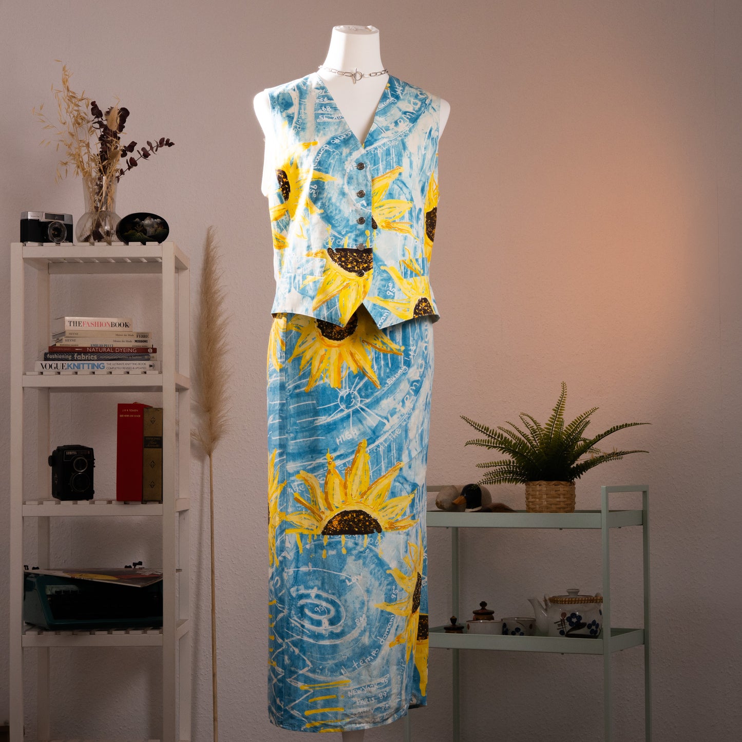 Archival Iceberg SS1994 Runway Linen Two-Piece Set – sky blue linen with oversized pop art sunflower and weather chart print in yellow, white and brown, sleeveless V-neck button-front vest top with pointed hem, matching midi wrap skirt, Gilmar Made in Italy, museum-quality 90s couture grail, product shot on dress form