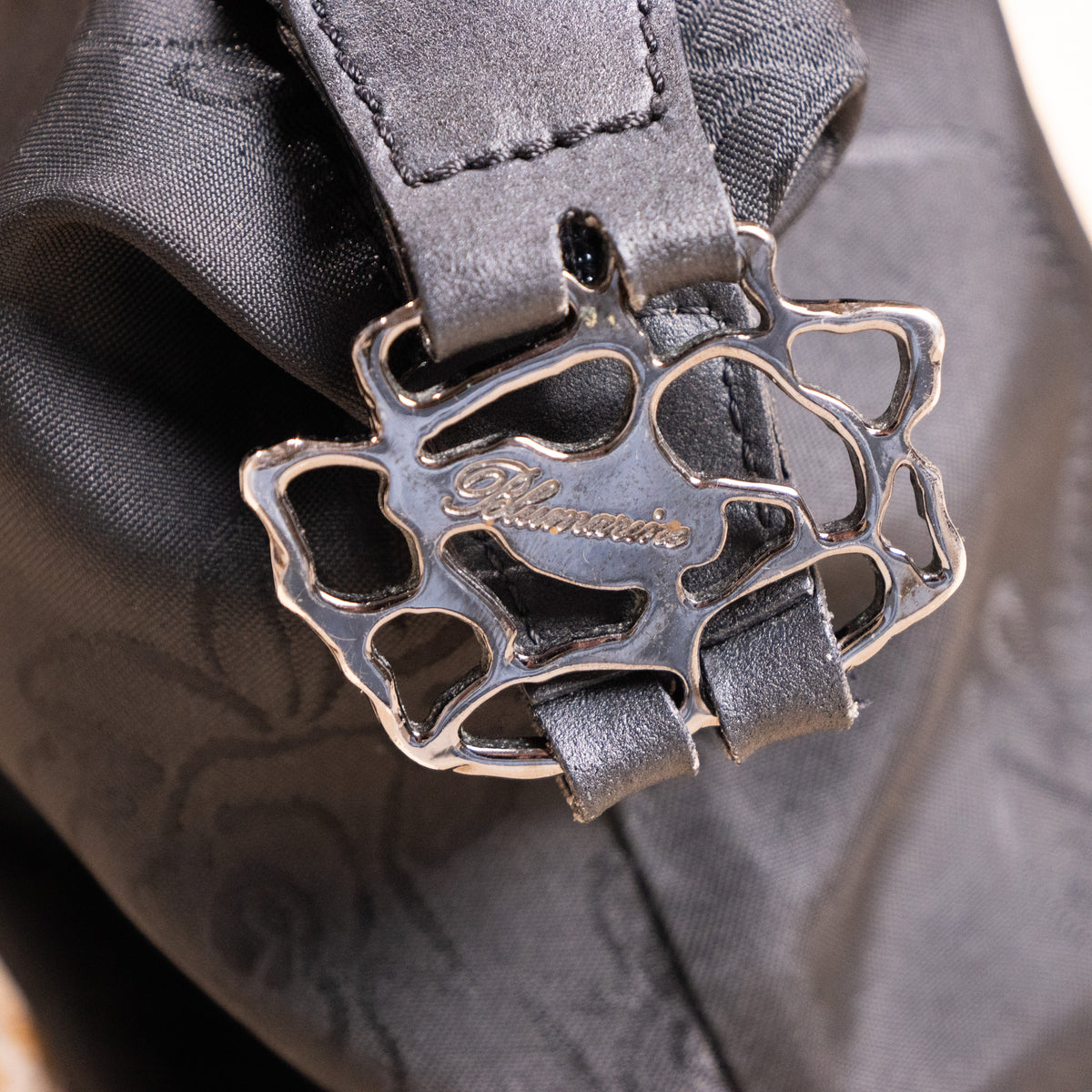 Close-up of sculptural silver-tone rose-vine metal buckle with engraved Blumarine logo on the archival deadstock baguette bag.