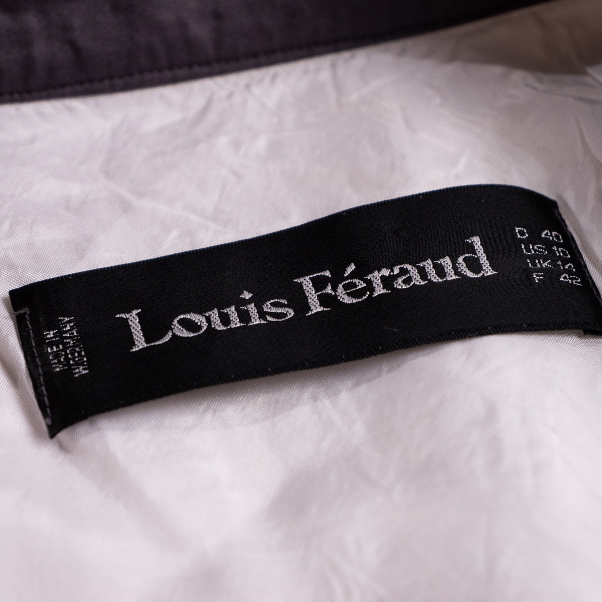 Close-up of the vintage Louis Féraud black woven satin neck label with vertical 'Made in W. Germany' text and European size matrix matrix D 40 US 10.
