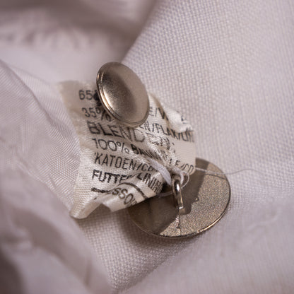 Authentic 1980s material composition tag showing 65% Flax-Linen and 35% Cotton blend next to the heavy custom-brushed metallic factory buttons.
