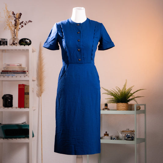 Archival Salvatore Ferragamo ultramarine blue wool crepe midi dress from the late 1970s with scalloped edges and logo buttons, front view on a gallery mannequin.
