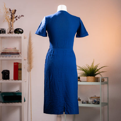 Rear view of the vintage Salvatore Ferragamo tailored wool dress showcasing the structured shoulder pad silhouette and inverted box-pleat walking vent.
