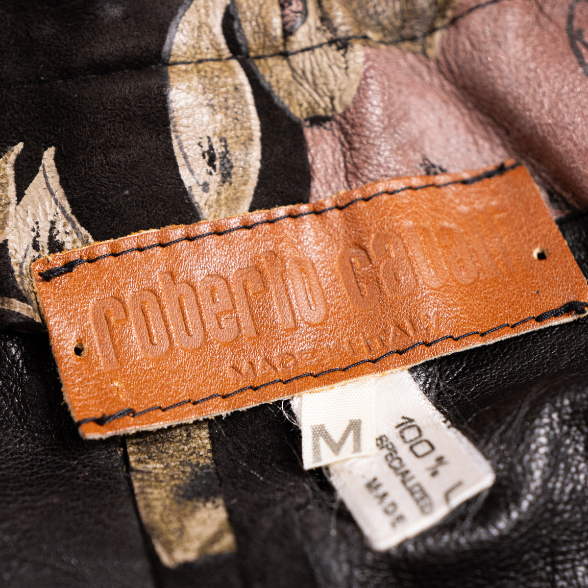 Immaculate interior view of the embossed brown leather Roberto Cavalli Made in Italy logo patch with specialized care tags.
