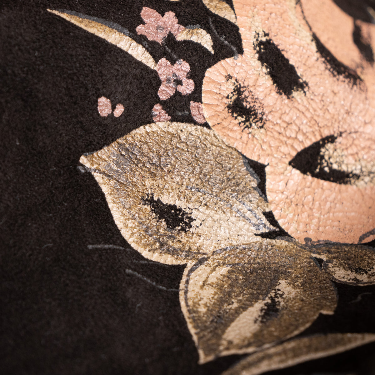 Macro studio shot showcasing the authentic age-related micro-crackle patina on the Roberto Cavalli floral printed leather texture.
