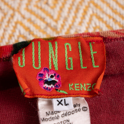 Close-up of the vintage orange Kenzo Jungle woven neck label with green text and embroidered purple flower motif.
