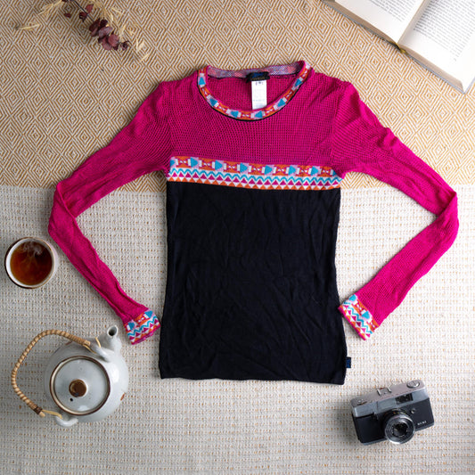 Christian Lacroix Jeans 90s Sheer Mesh Knit Top – fuchsia pink open-weave mesh upper body and long sleeves, black ribbed knit lower body, multicolour geometric zigzag intarsia trim at crew neckline, waist band and cuffs in orange, turquoise and white, colorblock silhouette, Made in France, flat lay editorial shot