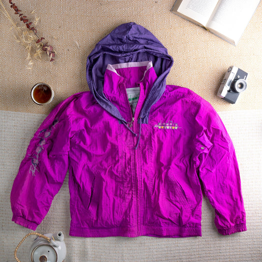 Vintage Diadora Performance 90s Colorblock Windbreaker Track Jacket – vibrant magenta pink nylon shell with contrasting purple hood lining, full zip front, two side zip pockets, elasticated cuffs, Diadora Performance logo embroidery at chest and sleeve script print, oversized shell suit fit, flat lay editorial shot