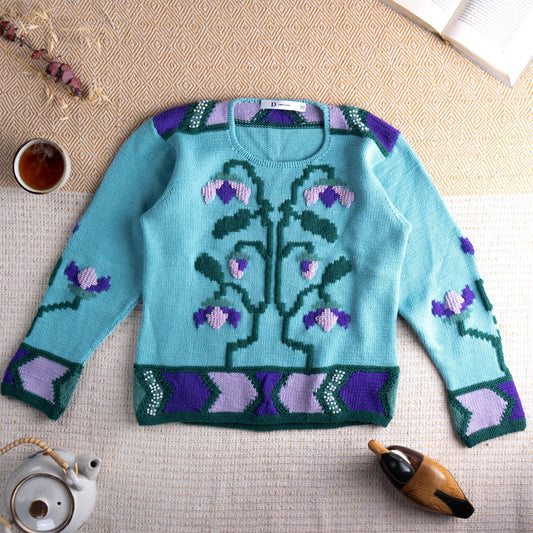Archival Dior D Uniforme Floral Beaded Wool Sweater – aqua mint blue wool knit with large-scale 3D intarsia bellflower and vine motif in forest green, lavender and purple, pearl bead embellishment at neckline and hem border, geometric chevron border in purple, lavender and green at cuffs and hem, crew neck, long sleeves, special event staff piece Made in Italy, flat lay editorial shot