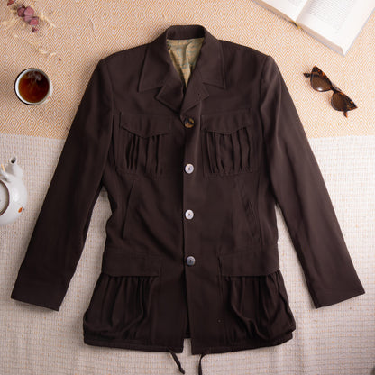 Archival Jean Paul Gaultier FW1999 "Classique" Smocked Safari Jacket – deep espresso brown wool-blend, wide notch lapel, three-button single-breasted front with mixed horn and white resin buttons, two large smocked chest patch pockets, smocked peplum hem with drawstring tie, two side welt pockets, beige lining, Automne Hiver 1999/2000 millennium collection, flat lay editorial shot