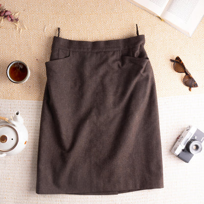 Archival Hermès Late 1980s Marron Foncé Virgin Wool Pencil Skirt – deep dark chocolate brown fine virgin wool, wide structured waistband with belt loops, two winged utility patch pockets at hips, centre front seam, straight pencil silhouette with back kick vent, Hermès Paris woven label, rare quiet luxury, flat lay editorial shot