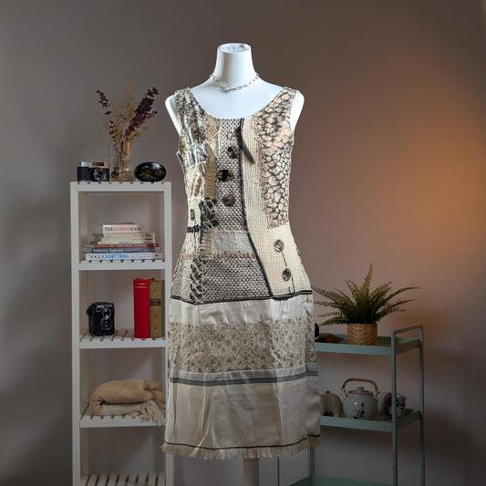 Save The Queen Archival Y2K Patchwork Midi Dress – ivory and grey mixed-media construction combining snake-print silk, diamond-weave linen, crochet lace and satin panels, asymmetric centre-front placket with large dark resin button closures, scoop neckline, sleeveless, ivory satin hem band with floral embroidery and fringe trim, art-to-wear, Marco Fantini Firenze, product shot on dress form