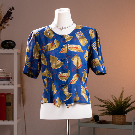 Archival Pierre Balmain Paris 80s Asymmetrical Peplum Blouse – cobalt blue fluid crepe with bold abstract geometric print in gold, red and white, round neckline, short puff sleeves, button-front, asymmetric peplum hem, power shoulder silhouette, museum quality, product shot on dress form