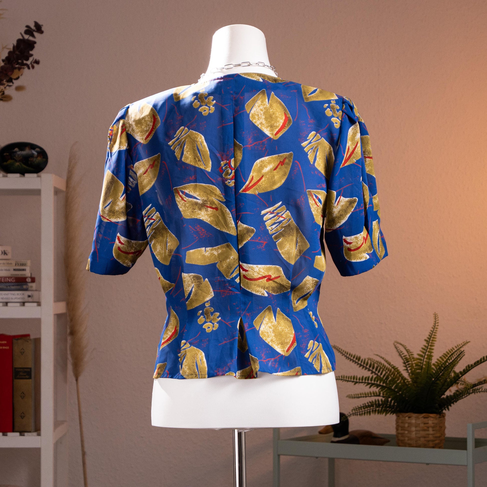 back view Archival Pierre Balmain Paris 80s Asymmetrical Peplum Blouse – cobalt blue fluid crepe with bold abstract geometric print in gold, red and white, round neckline, short puff sleeves, button-front, asymmetric peplum hem, power shoulder silhouette, museum quality, product shot on dress form
