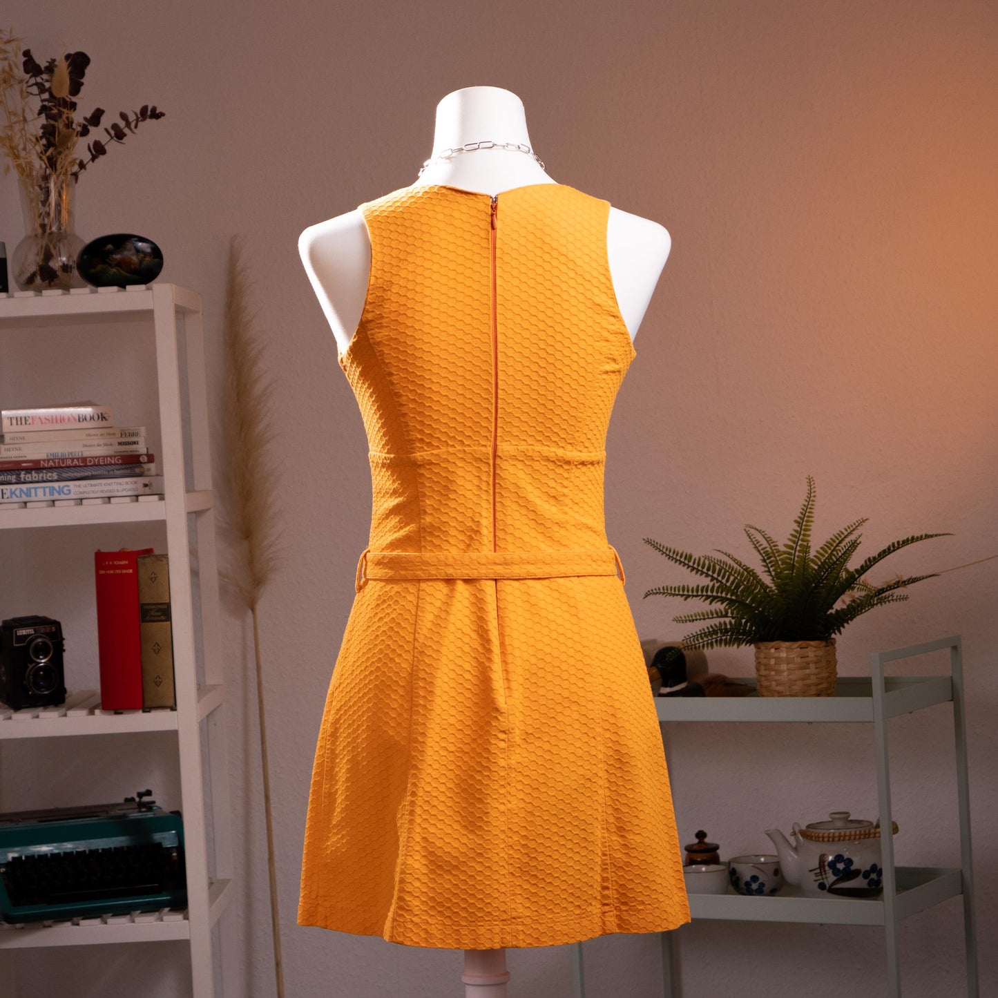 back view Archival Iceberg Jeans 90s Mod Revival Mini Dress – saffron yellow textured cotton piqué, deep V-neckline, sleeveless, A-line silhouette with double silver ring-buckle self-belt at waist, mod retro aesthetic, product shot on dress form