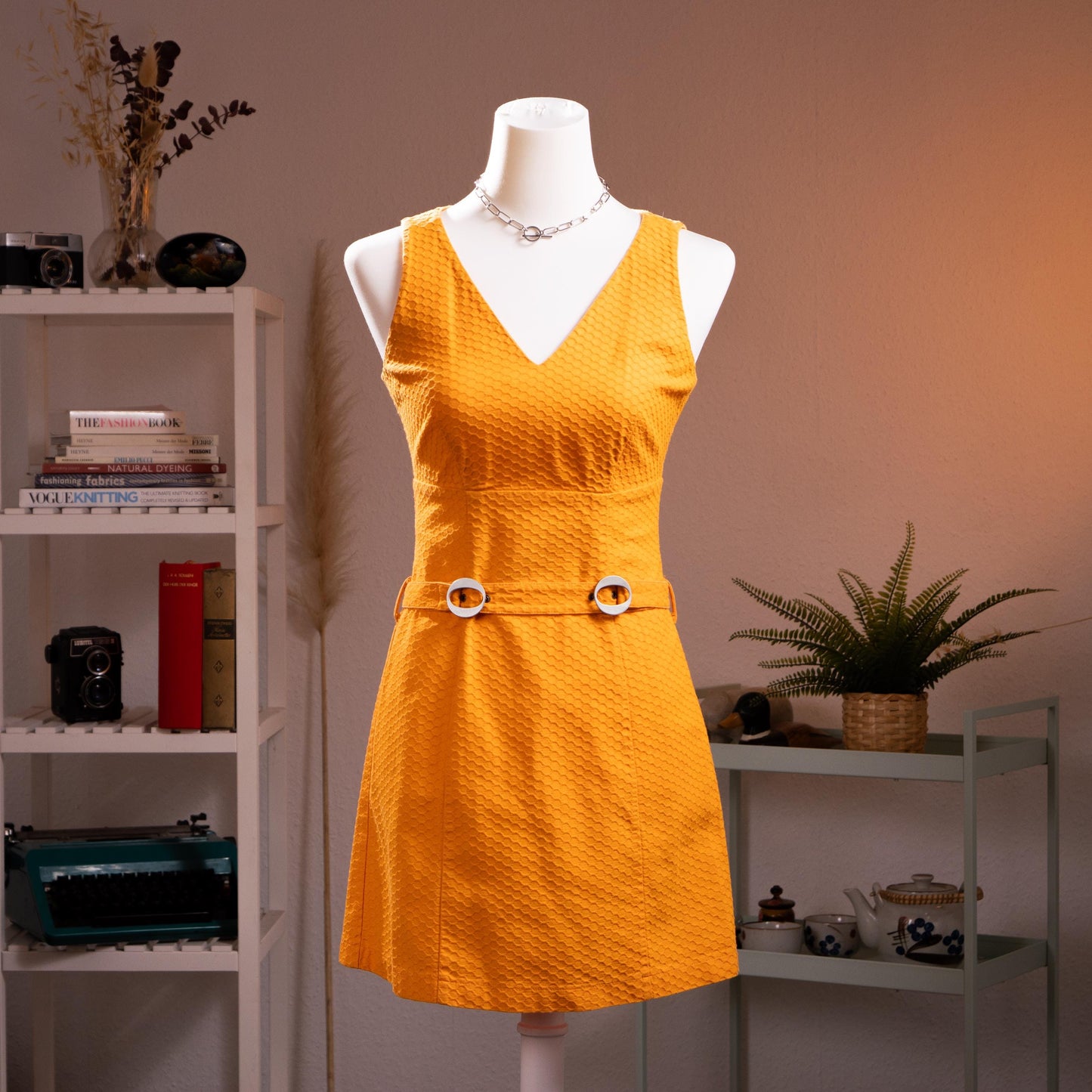 Archival Iceberg Jeans 90s Mod Revival Mini Dress – saffron yellow textured cotton piqué, deep V-neckline, sleeveless, A-line silhouette with double silver ring-buckle self-belt at waist, mod retro aesthetic, product shot on dress form