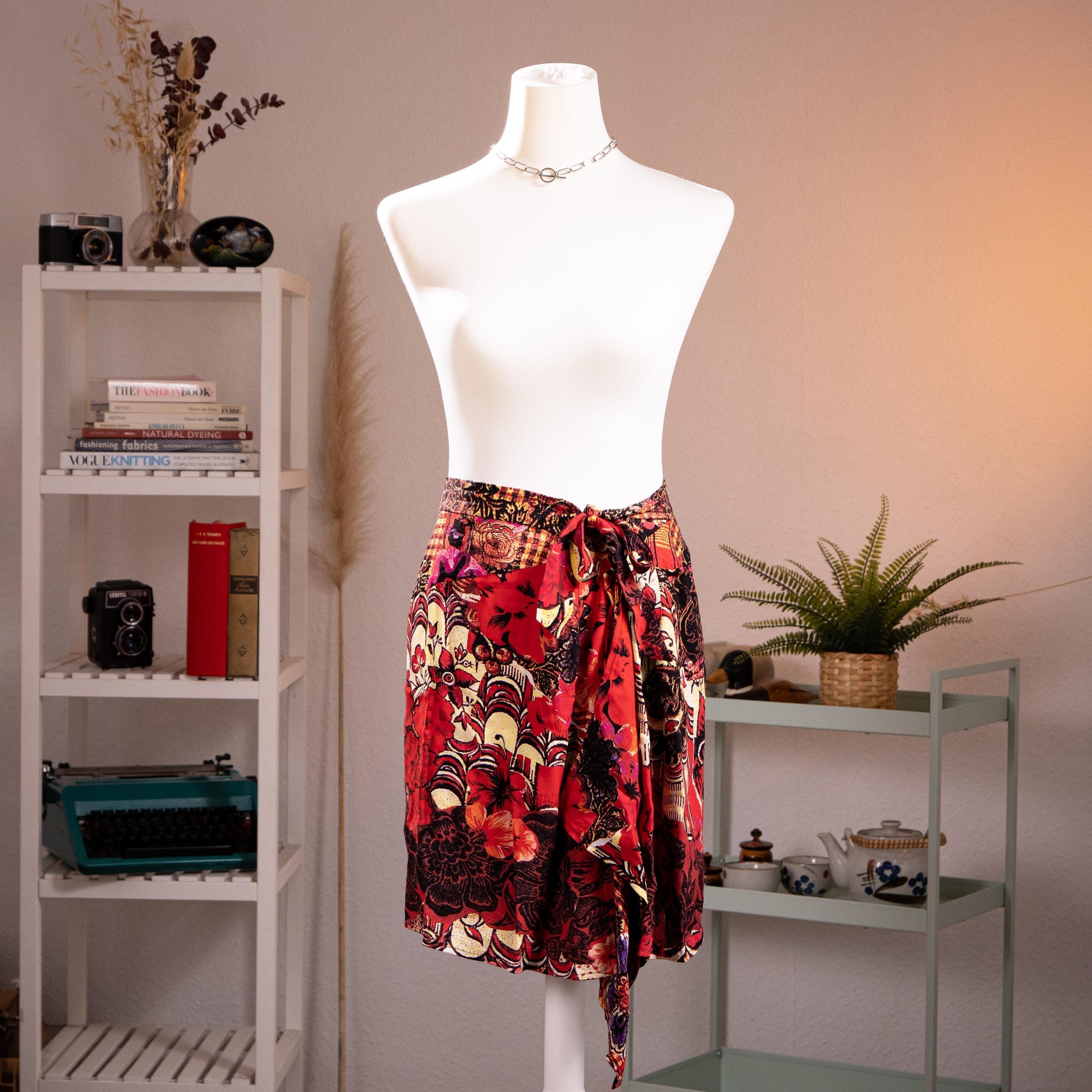 back view Archival Christian Lacroix FW96 Deadstock Asymmetric Wrap Skirt – bold maximalist floral print in crimson red, black, gold and purple on silk-feel fabric, self-tie bow waist, dramatic asymmetric handkerchief hem, product shot on dress form