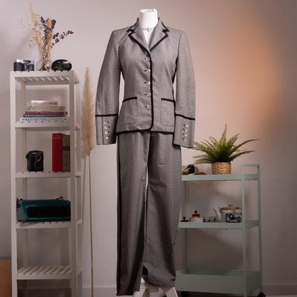 Archival Rena Lange RED 90s Virgin Wool Houndstooth Suit – silver grey fine virgin wool houndstooth blazer and wide-leg flared trousers set, notch lapel with black velvet piping trim, four silver coin buttons front, two piped flap pockets, wide turn-back cuffs with coin button detail, high-waist wide-leg trousers, Falber Italy, product shot on dress form