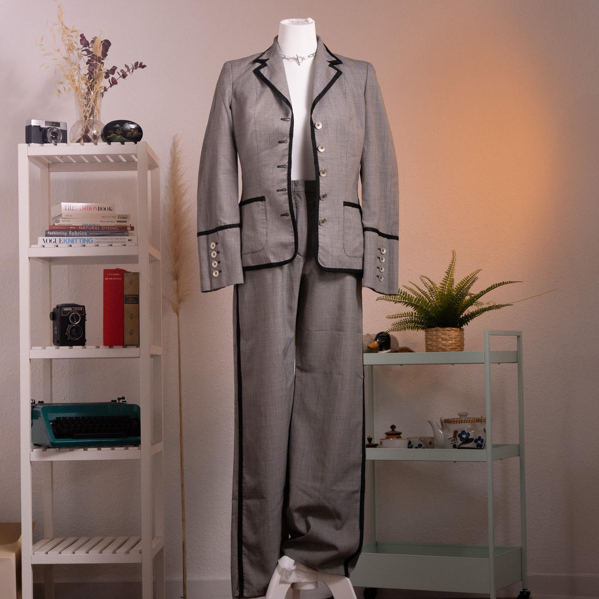 front Archival Rena Lange RED 90s Virgin Wool Houndstooth Suit – silver grey fine virgin wool houndstooth blazer and wide-leg flared trousers set, notch lapel with black velvet piping trim, four silver coin buttons front, two piped flap pockets, wide turn-back cuffs with coin button detail, high-waist wide-leg trousers, Falber Italy, product shot on dress form