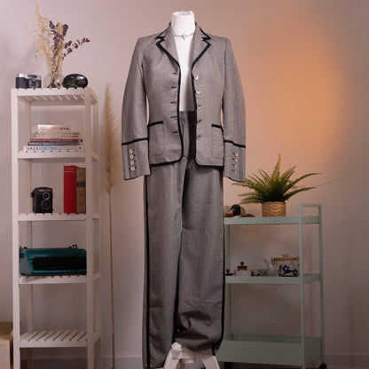 front Archival Rena Lange RED 90s Virgin Wool Houndstooth Suit – silver grey fine virgin wool houndstooth blazer and wide-leg flared trousers set, notch lapel with black velvet piping trim, four silver coin buttons front, two piped flap pockets, wide turn-back cuffs with coin button detail, high-waist wide-leg trousers, Falber Italy, product shot on dress form
